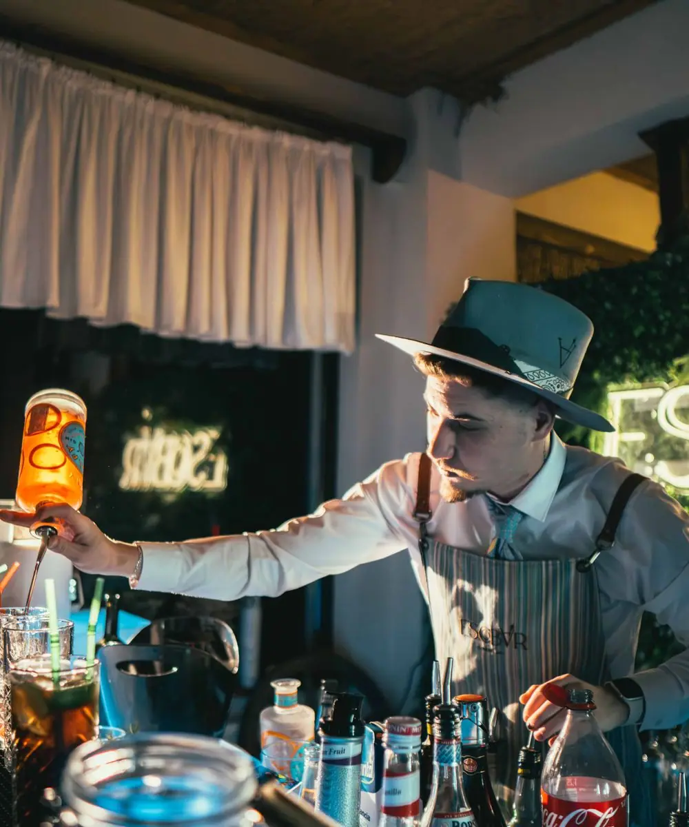 A professional bartender in an apron preparing drinks behind the bar