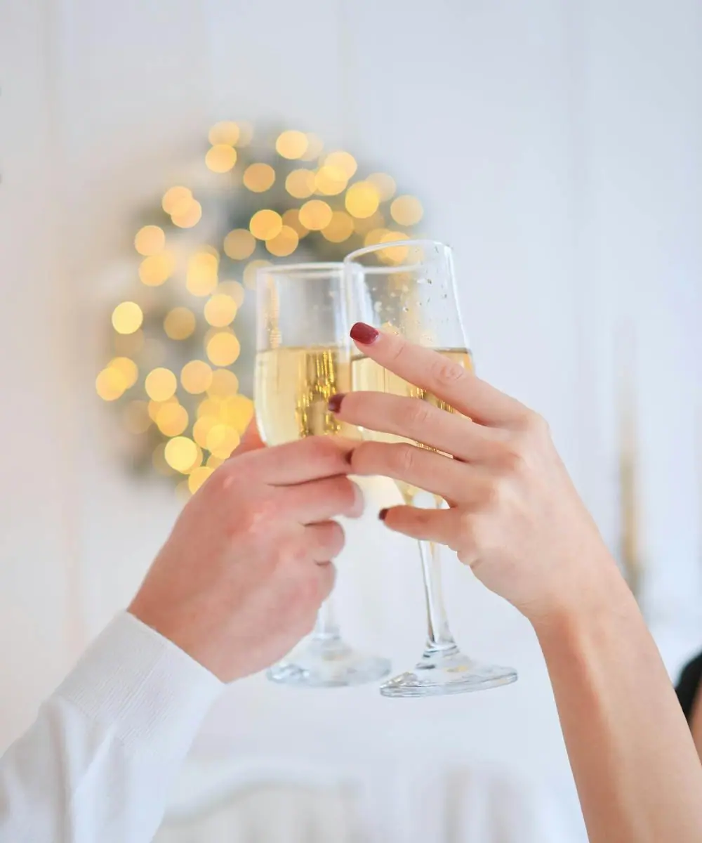 Champagne being poured into a row of coupe glasses for a toast