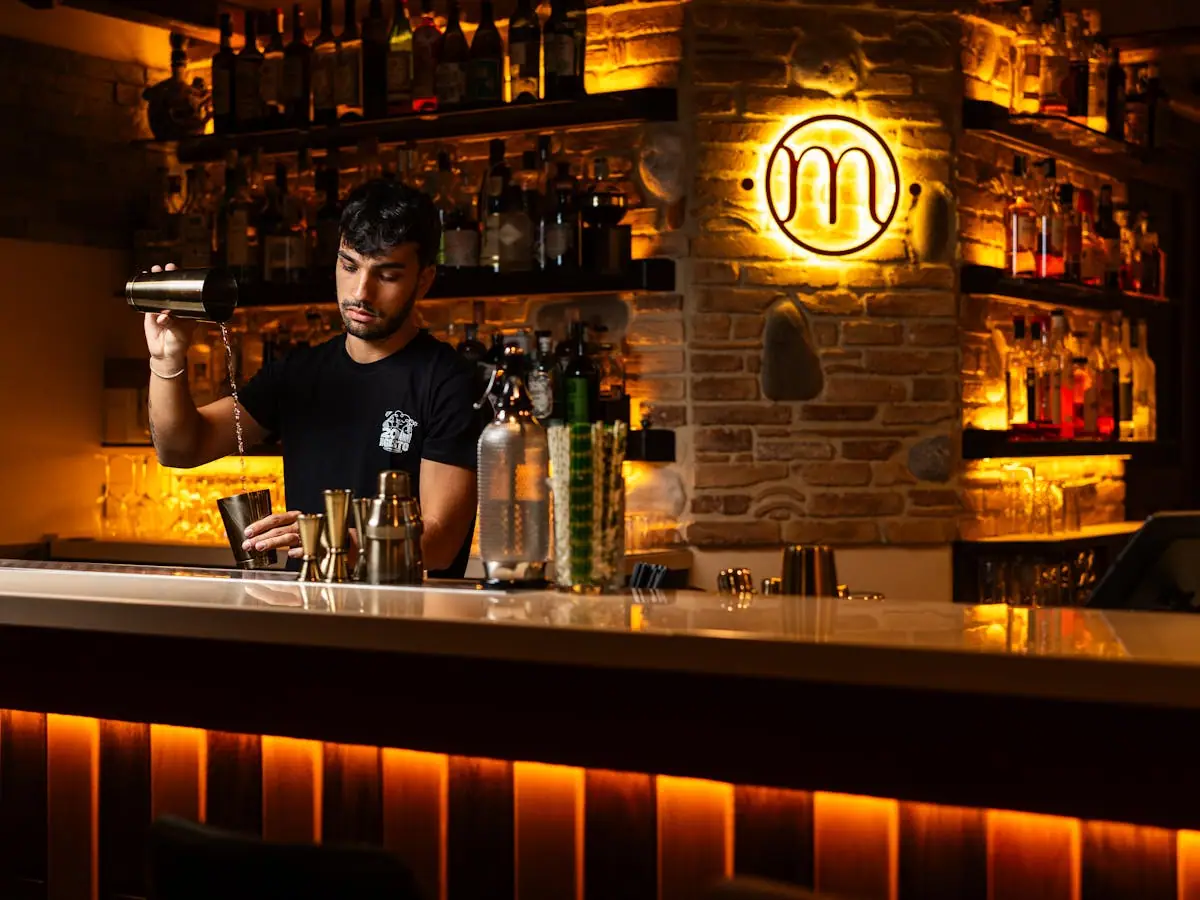 A bartender straining a freshly shaken craft cocktail into a glass